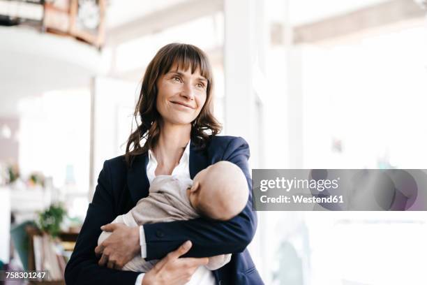 businesswoman in cafe holding sleeping baby - working mum stock pictures, royalty-free photos & images