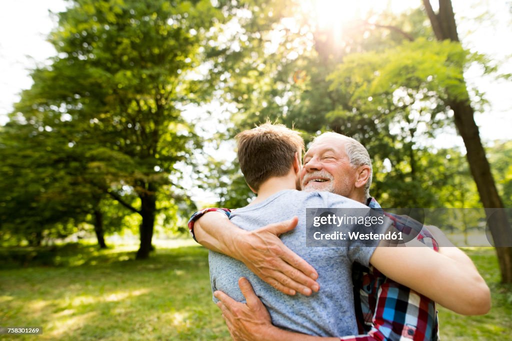 Happy senior father hugging his adult son in a park