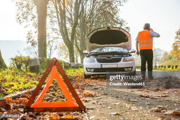 back view of man on cell phone having a car breakdown - indumento fluorescente foto e immagini stock