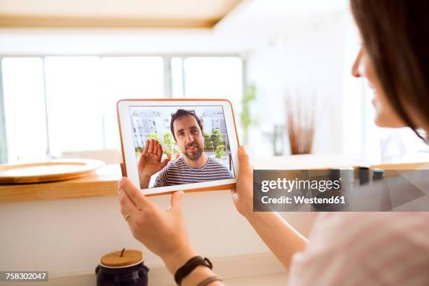 young woman using tablet for video chat at home - lange afstandsrelatie stockfoto's en -beelden