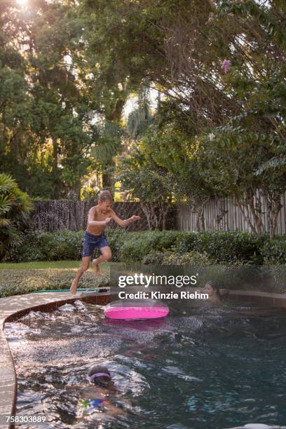 children swimming in garden pool, young boy jumping in, mid-air - orlando florida family stock pictures, royalty-free photos & images