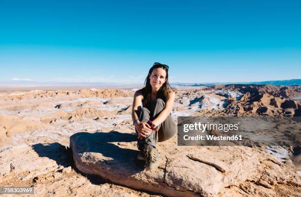 chile, atacama desert, smiling woman sitting on a rock at sunlight - valle de la muerte stock pictures, royalty-free photos & images