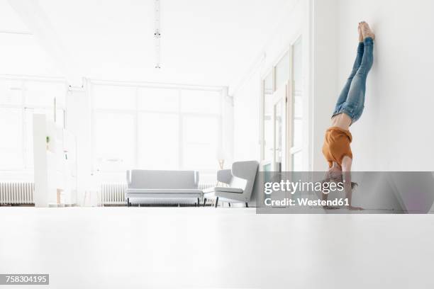 woman doing handstand in a loft - lehnend stock-fotos und bilder