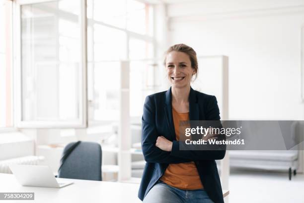 portrait of smiling businesswoman in a loft - kompetenz stock-fotos und bilder