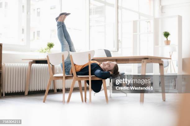 woman doing gymnastics on chairs in a loft - piernas en el aire fotografías e imágenes de stock