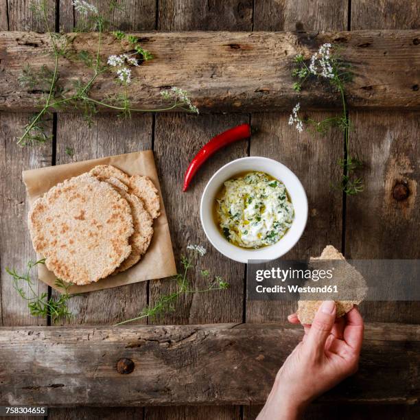 hand with home-baked naan bread and bowl of curd dip - dip stockfoto's en -beelden