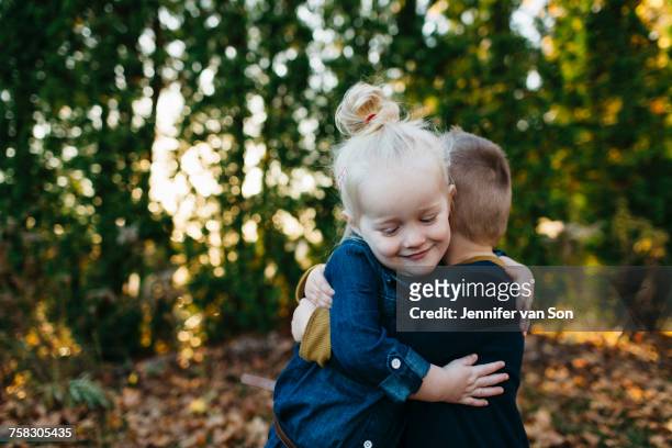 cute female toddler hugging twin brother in autumn garden - whitby ontario canada stock pictures, royalty-free photos & images