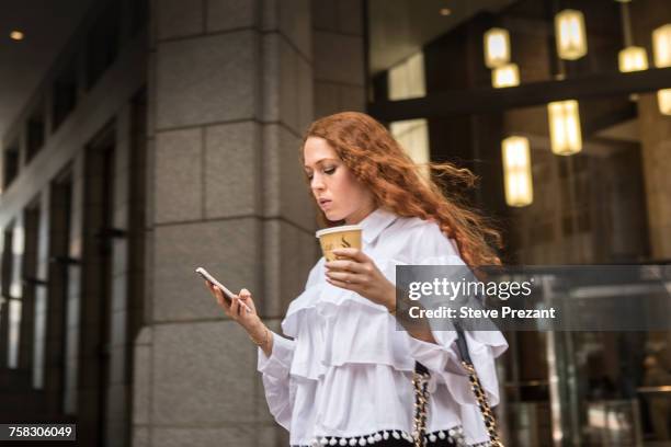 young businesswoman with takeaway coffee looking at smartphone on sidewalk, new york, usa - businesswoman nyc stock pictures, royalty-free photos & images