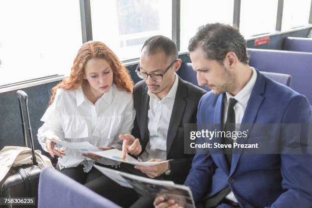 young businesswoman and businessmen looking at paperwork on passenger ferry - commuter ferry stock pictures, royalty-free photos & images
