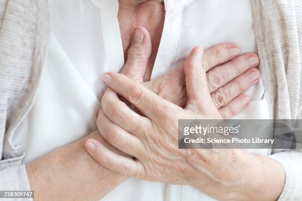 senior woman holding chest - heart attack stockfoto's en -beelden