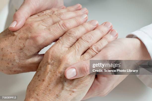 female doctor examining senior patients hands - hautmerkmal stock-fotos und bilder