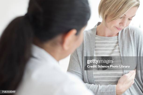 female doctor listening to patient - weibliche brust stock-fotos und bilder