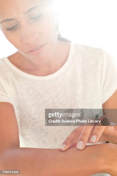 woman inspecting mole on arm - mole stock pictures, royalty-free photos & images