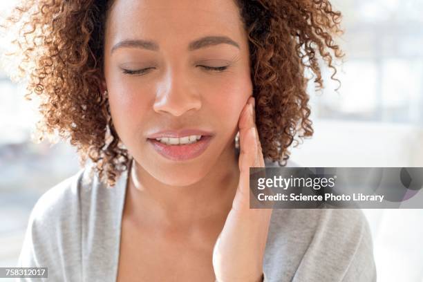 portrait of woman touching face - sensitivity in tooth stock-fotos und bilder