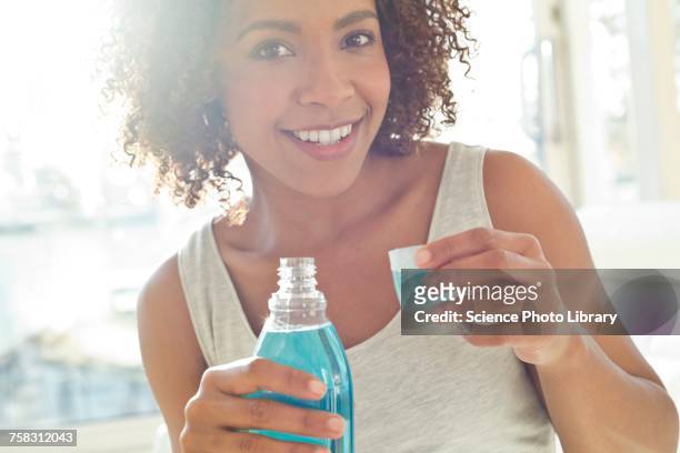 portrait of woman using mouthwash - mouthwash stock-fotos und bilder