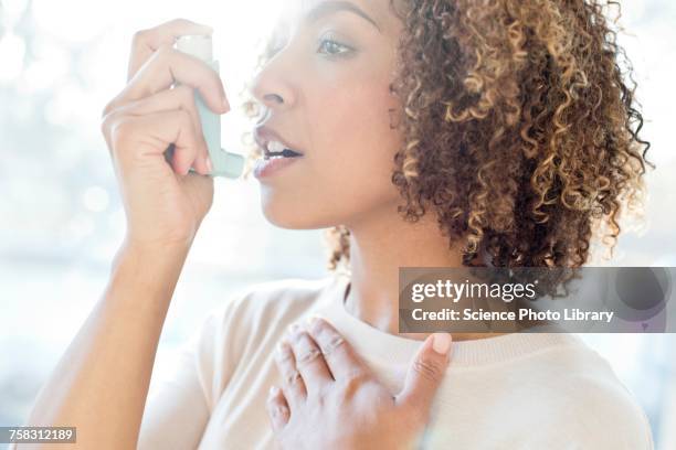 mid adult woman using inhaler - asmático fotografías e imágenes de stock