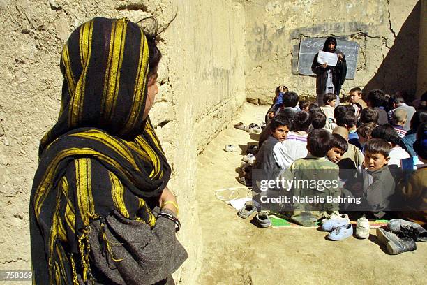 An Afghan schoolgirl watches a boys class using new textbooks distributed at Kabul's Amir Dost Mohammad Khan Secondary School March 25, 2002 in...