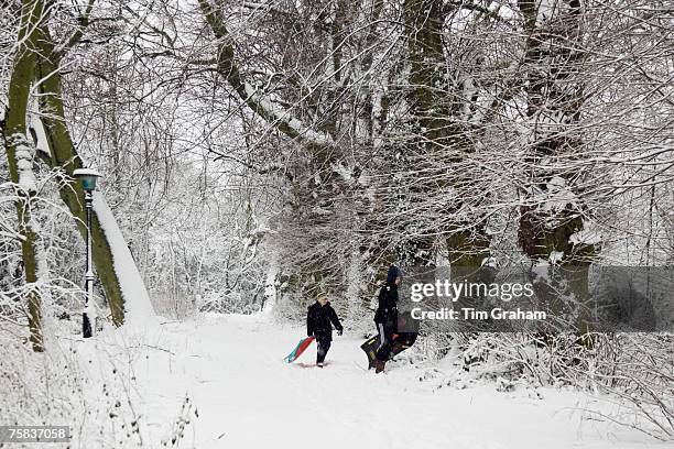 Boys carry sledges across snow-covered Hampstead Heath, North London, United Kingdom