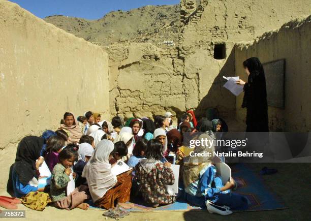 Afghan schoolgirls use newly distributed textbooks, during a lesson in a destroyed classroom at Kabul's Amir Dost Mohammad Khan Secondary School...