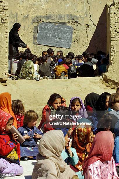 Afghan school children wait for textbooks to be distributed as they sit in makeshift classrooms at Kabul's Amir Dost Mohammad Khan Secondary School...