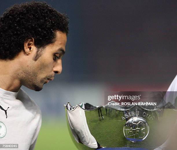 Saudi Arabia's football team captain Yasser Al Qahtani peeks inside the Asian Football Cup 2007 trophy at the Gelora Bung Karno stadium during a...