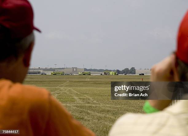 Spectators watch wreckage and emergency response vehicles on the runway at the 2007 Vectren Dayton International Airshow at Dayton International...