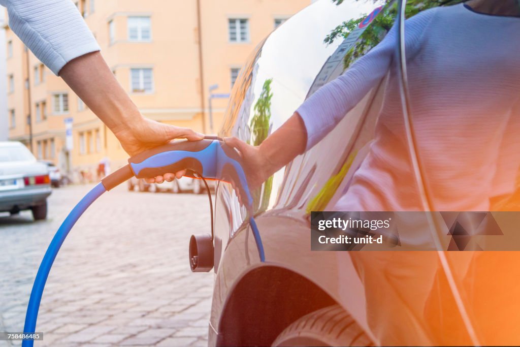 Man Charging Electric Car On Street In City