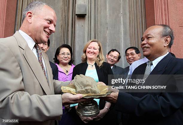 Ambassador to Cambodia, Joseph A. Mussomeli , offers a sandstone apsara statue face to Him Chhem , deputy minister of culture and fine arts at the...