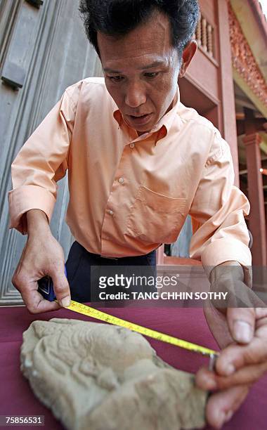 Cambodian man measures part of a sandstone apsara statue being returned in Phnom Penh, 30 July 2007, during a repatriation ceremony for Khmer...