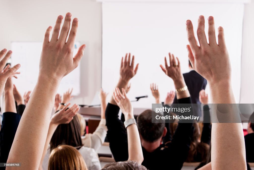 Menschen mit erhobenen Armen im Hörsaal während des Seminars