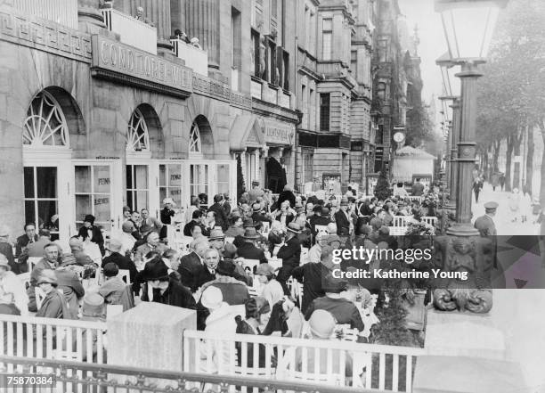 View of diners at a crowded sidewalk cafe on Kurfurstendamm, Berlin, Germany, 1926. A movie theatre is next to the cafe.