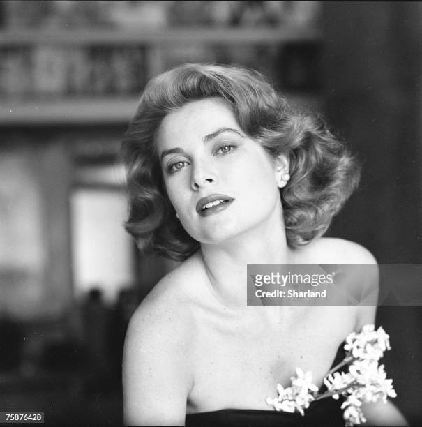 Portrait of American actress Grace Kelly in a strapless gown with a sprig of flowers tucked into her bodice, Hollywood, California, March 1954. The...