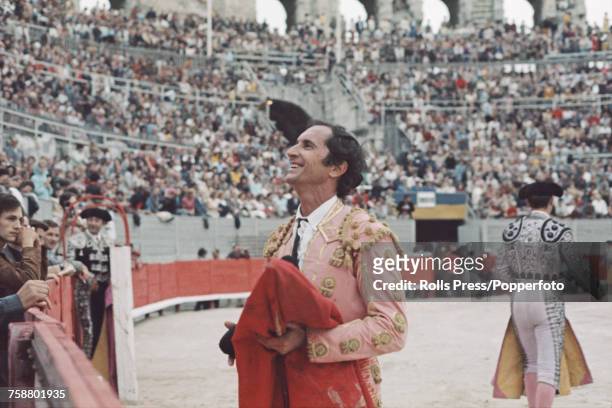 Spanish bullfighter Luis Miguel Dominguin pictured holding a red cape in the Arles Amphitheatre bullring during a bullfighting event in Arles, France...