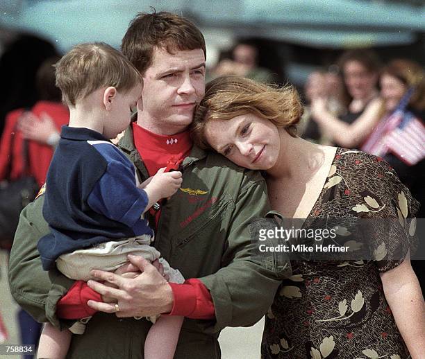 Amy Hayes rests her head on the shoulder of her husband Andrew as he holds their two-year old son Ethan while walking off the tarmac at Naval Air...