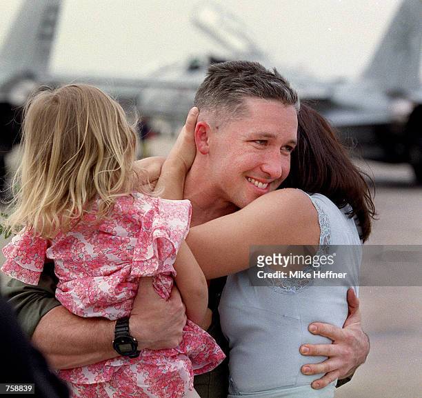Pilot Zach Mosedale embraces his daughter Zoe and wife Cara at Naval Air Station Oceana March 26, 2002 in Virginia Beach, VA. The F-14 Tomcat...