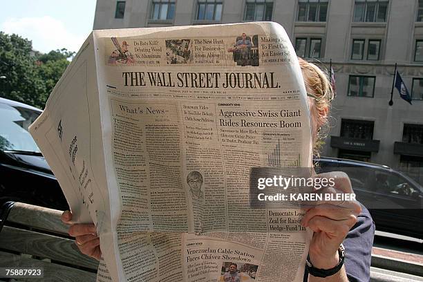 Woman reads the Wall Street Journal while siiting on "K" Street 31 July, 2007 in Washington, DC. Rupert Murdoch's News Corp. Appears to have won...