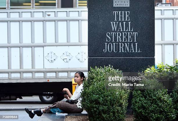 Woman sits in front of a sign outside a Wall Street Journal office on Avenue of the Americas July 31, 2007 in New York City. Rupert Murdoch's News...