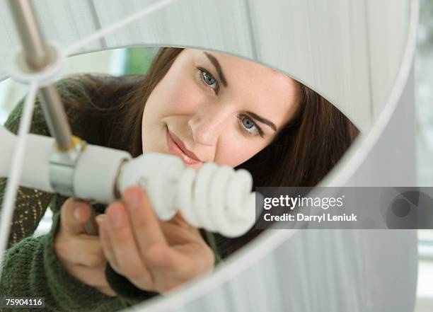 woman installing bulb - energy efficient lightbulb stock-fotos und bilder