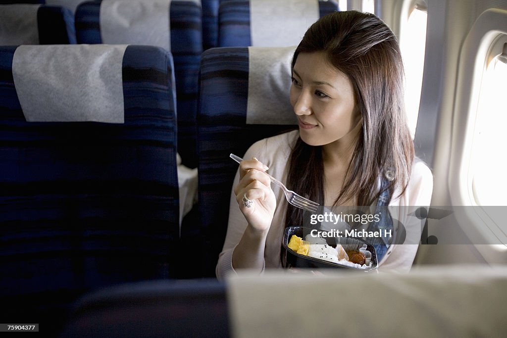 Woman eating meal in airplane
