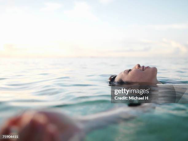 woman floating in sea, smiling, profile - calm sea stock-fotos und bilder