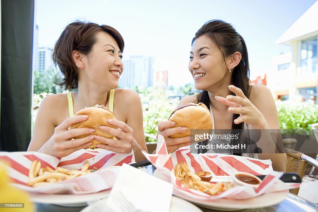 Women holding hamburgers, smiling
