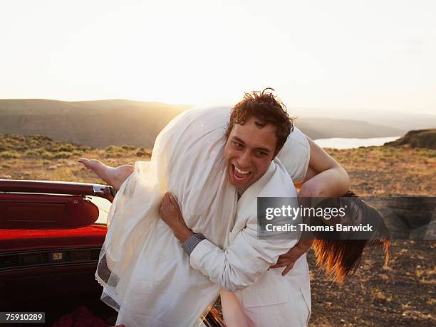 groom carrying bride over shoulder, laughing - bruidegom stockfoto's en -beelden