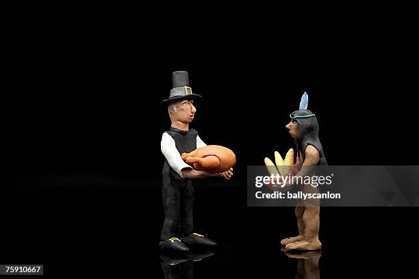 clay model of pilgrim and native american indian figures with a turkey and bowl of corn - corn on black stockfoto's en -beelden