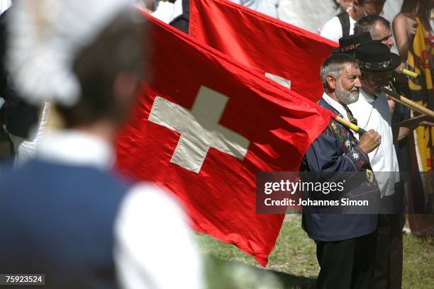 Flag waverswait with Swiss flags during the Ruetli celebrations on August 1 near Luzern, Switzerland. Every year the reenactment of the forming of...