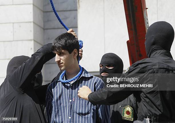 Masked Iranian policeman tightens the noose around the neck of Hossein Kavousifar before hanging him in public in central Tehran, 02 August 2007. Two...