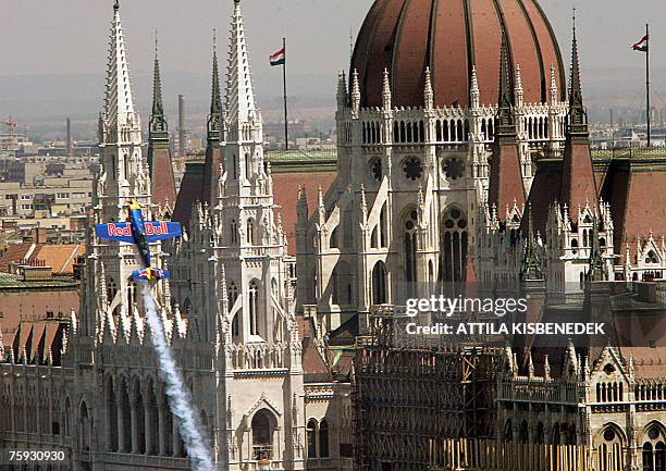 Hungarian aerobatics pilot Peter Besenyei of Red Bull team flies in front of the parliament building with his Extra 300S airplane in Budapest...