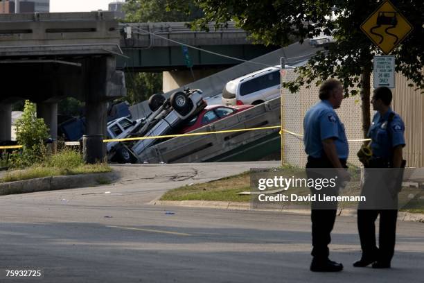 Two police officers stand watch where the Interstate 35 bridge severed and cars piled up on the east side of the Mississippi River August 2, 2007 in...