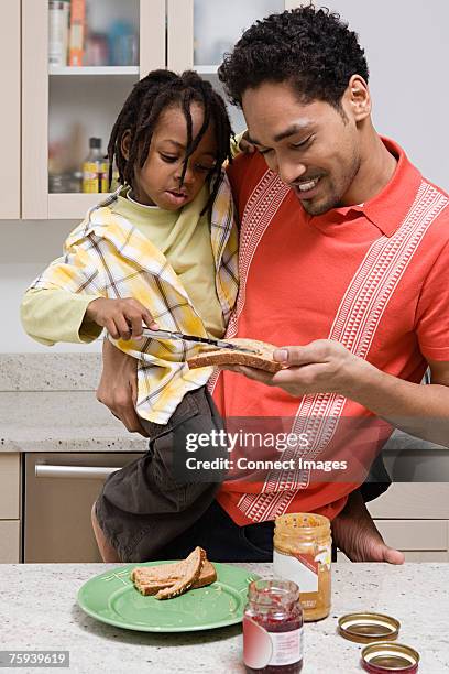 a boy helping his father in the kitchen - peanut butter and jelly sandwich on plate stock pictures, royalty-free photos & images