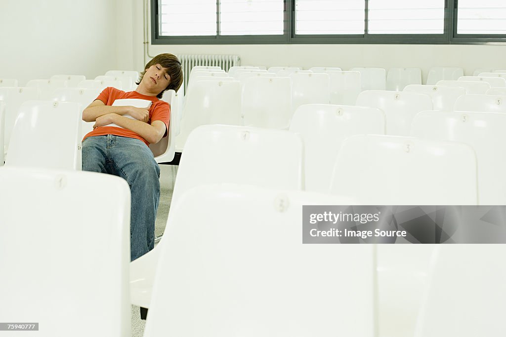 Boy sleeping in lecture theatre