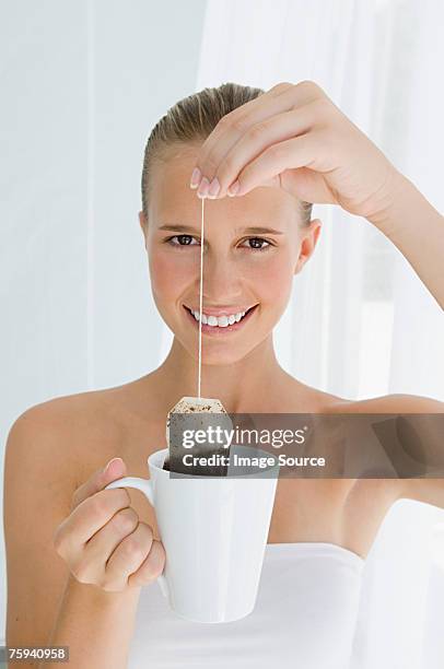 young woman holding tea bag - herbal tea bag stock pictures, royalty-free photos & images